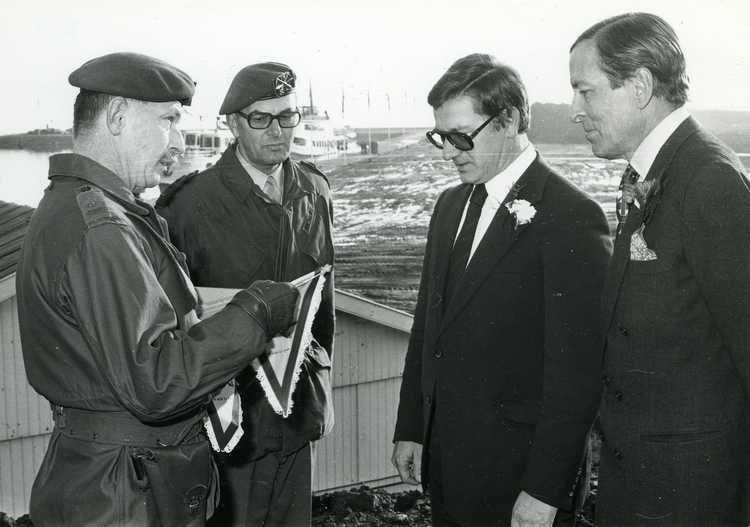 Openstelling voor verkeer van de Houtribdijk (Enkhuizen-Lelystad) door Z.K.H. Prins Claus. Lt.Kol. F. Richert, commandant van een peloton soldaten, dat het dijktracé gedeeltelijk te voet aflegde, overhandigt een herinneringsvaantje aan Prins Claus en Min.